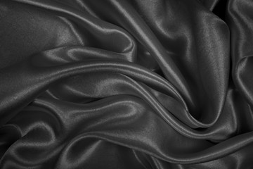Black silk texture luxurious satin for abstract background. Dark tone of fabric