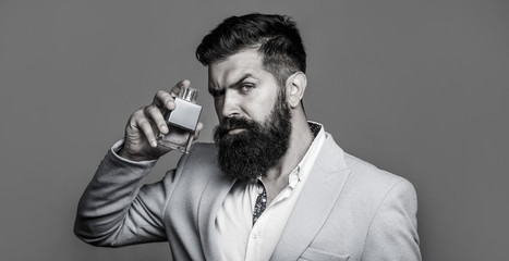 Man perfume, fragrance. Masculine perfume. Male fragrance and perfumery, cosmetics. Bearded man holding up bottle of perfume. Fashion cologne bottle. Bearded male prefers expensive fragrance smell.