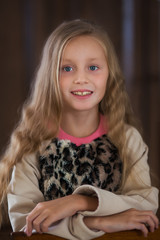 Cute little girl with long hair on a brown background close-up