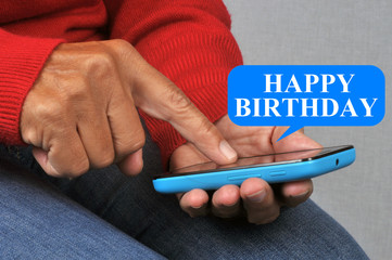 Someone sending the happy birthday message with his smartphone