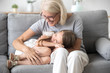 © fizkes - Happy granddaughter lying on grandmother knees, having fun together