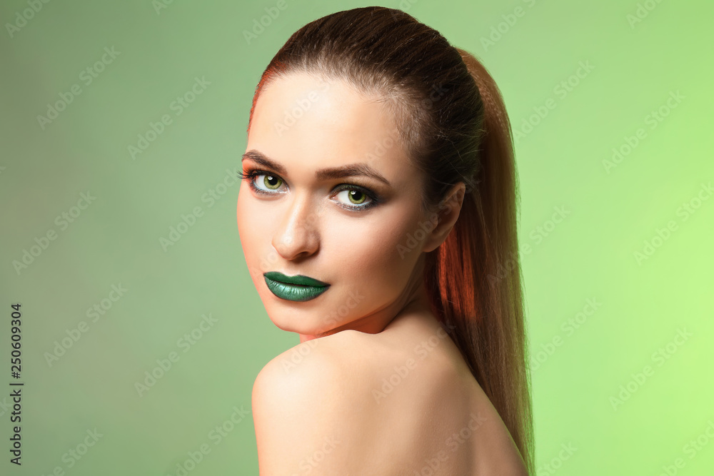 Beautiful young woman with bright makeup on color background