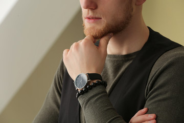 Fashionable young man with watch indoors, closeup