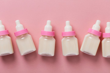 Baby bottles with milk on a pastel pink background