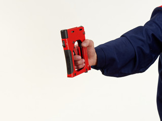 man in overalls holds tool stapler on white background.