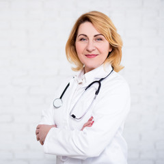 Wall Mural - mature female doctor or nurse posing over white wall