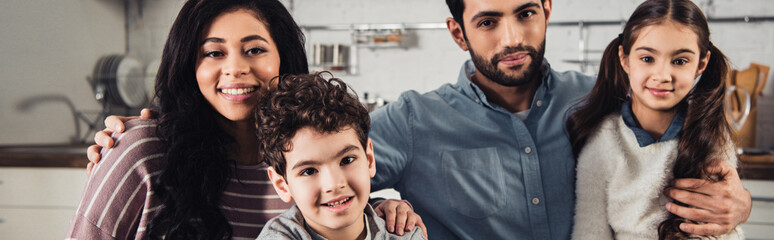 cheerful hispanic family smiling while looking at camera at home