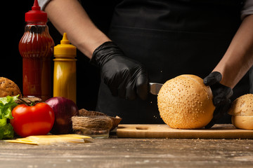 Chef prepares fresh sesame buns for burger cooking, with ingredients on the background, restaurant business, fast food, tasty food, gastronomy, cooking, menu