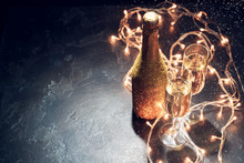 Picture Of Golden Champagne Bottle, Two Wine Glasses, Burning Garlands