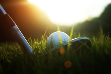 Golf Club And Golf Ball Close Up In Grass Field With Sunset. Golf Ball Close Up In Golf Coures At Thailand