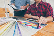 © Ngampol - Teamwork of young creative designers working on project together and choose color swatch samples for selection coloring on digital graphic tablet at workspace