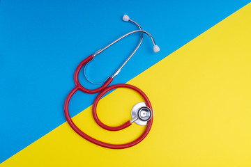 Wall Mural - Stethoscope on blue and yellow background with selective focus