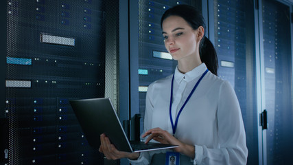 Aufkleber - Confident and Beautiful Female IT Engineer is Working on Laptop in Data Center while Standing Before Server Rack. Running Diagnostics or Doing Maintenance Work.