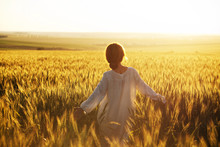 Happy Woman Walks Over Wheat Field In The Rays