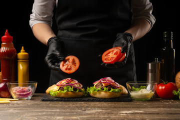 Wall Mural - Chef puts tomato rings on a burger, on the background of the ingredients. Horizontal photo, Tasty and unhealthy food, fast food, homemade recipes, restaurant, catering, recipe book
