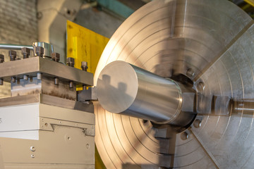 The big industrial CNC lathe machine cutting the steel rod