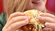 Happy young woman eating delicious burger and smiling. Close up