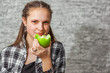 © pavel siamionov - portrait of young teenager brunette girl with long hair eat green apple on gray wall background