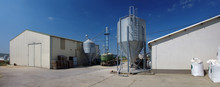 Modern Farm Buildings With Silos And Tractor