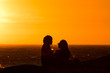 © laura - Sunset silhouette: same sex couple of girls at sunset in Camps Bay Tidal Pool, Cape Town, South Africa