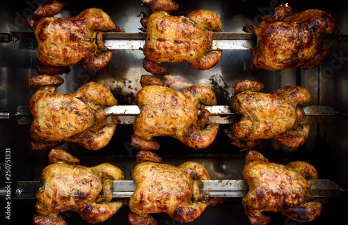 Fotomural Rows of hot roasted skewered whole rotisserie chickens, in Colombia, South America