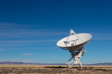 Wall Mural - very large array distant view of radio antenna against a blue sky, gold fields and purple mountains,