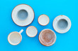 © 9dreamstudio - Kitchen concept. Crockery kit. Empty ceramic plates and mugs on blue background top view