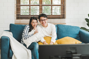 Wall Mural - Asian couple lifestyle, man and woman watching TV movies at home, family lifestyle relax and recreation concept