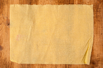 Wall Mural - Grunge crumpled yellow beige paper texture on wood background. Distressed and industrial background.