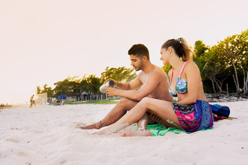 beach lifestyle portrait of young couple sitting on the sand