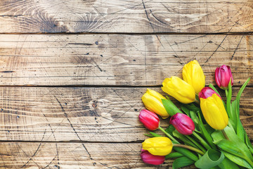 Bouquet of yellow and pink tulips on a wooden background.