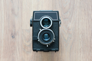 Old film camera with two lenses isolated on wooden background