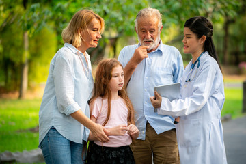 Wall Mural - Happy healthy family and doctor talking in park.