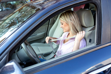 Wall Mural - Blonde woman putting the seatbelt before driving