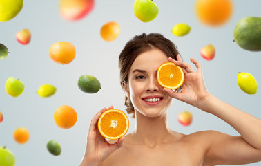 beauty and people concept - smiling young woman with oranges over grey background and citrus fruits