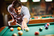 © luckybusiness - man aiming at pool ball to billiard game.