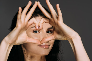 Wall Mural - beautiful tender woman showing heart sign isolated on grey