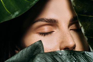 Wall Mural - beautiful woman with closed eyes posing with green palm leaves
