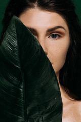 Wall Mural - beautiful woman with perfect skin posing with green palm leaf