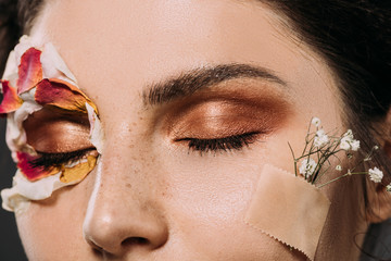 Wall Mural - close up of woman with makeup on closed eyes and flowers on face