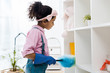 © LIGHTFIELD STUDIOS - cute african american chid dusting shelving unit