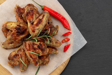 Wall Mural - Baked chicken wings with and sweet chili sauce on  wooden board over dark background with copy space