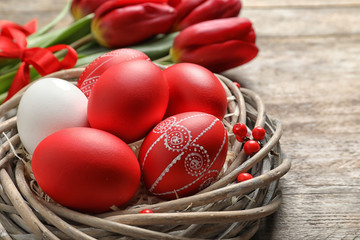 Wall Mural - Wicker nest with painted Easter eggs on table, closeup