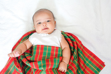 Newborn baby wear white dress and Thai traditional fabric called pa kao ma at bottom, white towel background with shadow