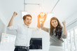 © Yingyaipumi - Businessman and Businesswomen team holding award trophy for show their victory.We are the champions! Successful business team with raised up hands in sunny modern workstation.