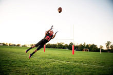 Football Player Catching Ball On Playing Field 