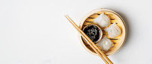 Traditional Chinese Steamed Dumplings Dim Sums In Bamboo Steamer With Sauces And Chopsticks On Light Surface With Copy Space. Asian Food Background.