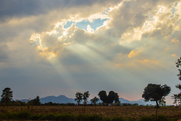 Wall Mural - Sunbeam shining through the cloud in the valley. Evening sunset with sun rays through the clouds.