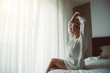 © Davide Angelini - Beatiful young woman in modern bedroom stretching after wake up in the morning