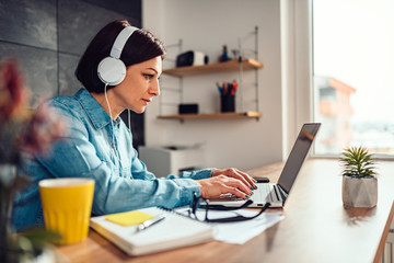 Woman using laptop and listening music on a headphones